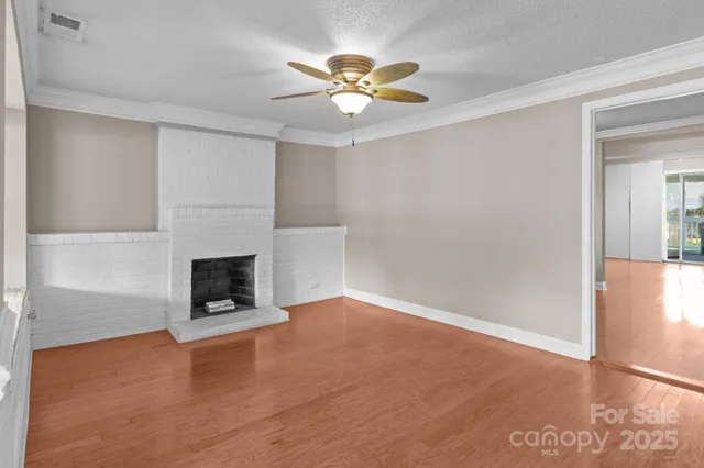 an empty room with ceiling fan and windows