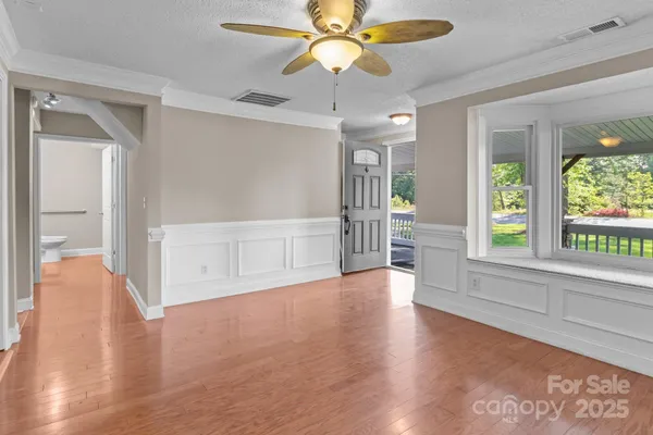 a view of an empty room with window and wooden floor