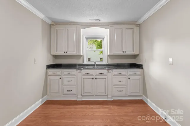 a view of kitchen with granite countertop white cabinets and window
