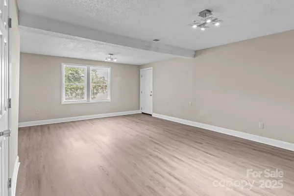 an empty room with wooden floor chandelier fan and windows