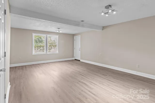 an empty room with wooden floor chandelier fan and windows