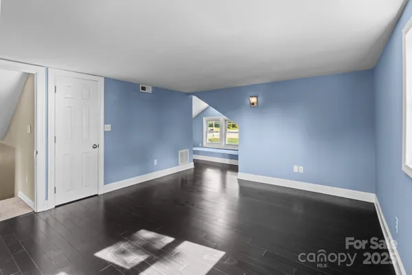 a view of an empty room with window and wooden floor