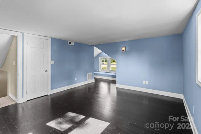 a view of an empty room with window and wooden floor