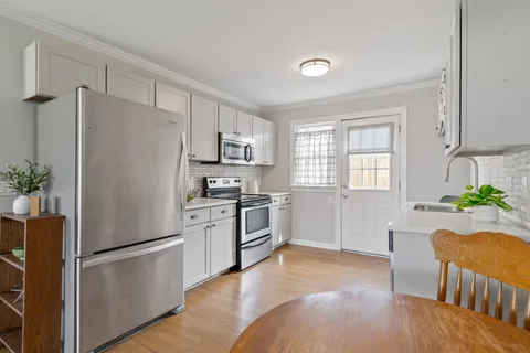 a kitchen with a refrigerator a stove a sink dishwasher and white cabinets with wooden floor