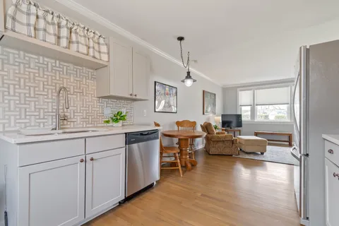 a kitchen with white cabinets and wooden floor