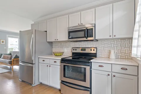 a kitchen with cabinets stainless steel appliances and wooden floor
