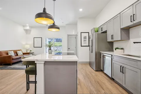 a kitchen with stainless steel appliances kitchen island granite countertop a sink cabinets and wooden floor