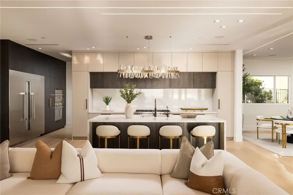 a living room with couches a coffee table and kitchen view with wooden floor