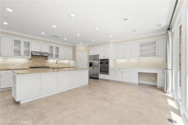 a large white kitchen with stainless steel appliances granite countertop a stove and a sink