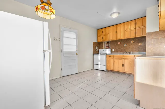 a view of a refrigerator in kitchen and a window in a room