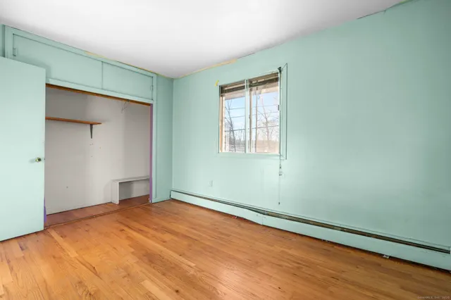 an empty room with wooden floor closet and windows