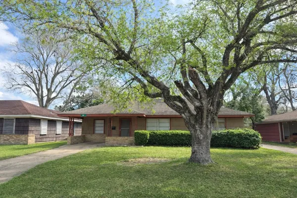 a front view of a house with a garden and trees