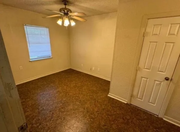 an empty room with a window and chandelier fan