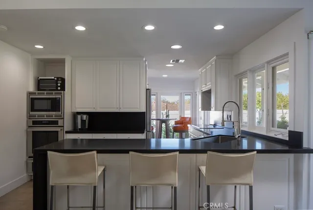 a kitchen with stainless steel appliances granite countertop a stove a sink and a microwave