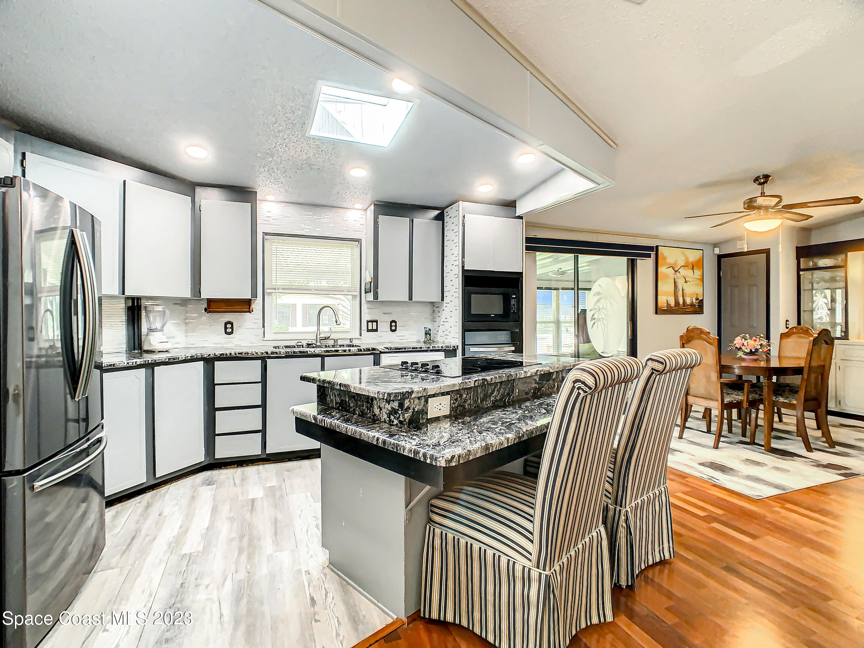 832 Periwinkle Circle Sebastian, FL 32976 - Photo 15 of 52 a kitchen with stainless steel appliances granite countertop a stove top oven a sink dishwasher a dining table and chairs with wooden floor
