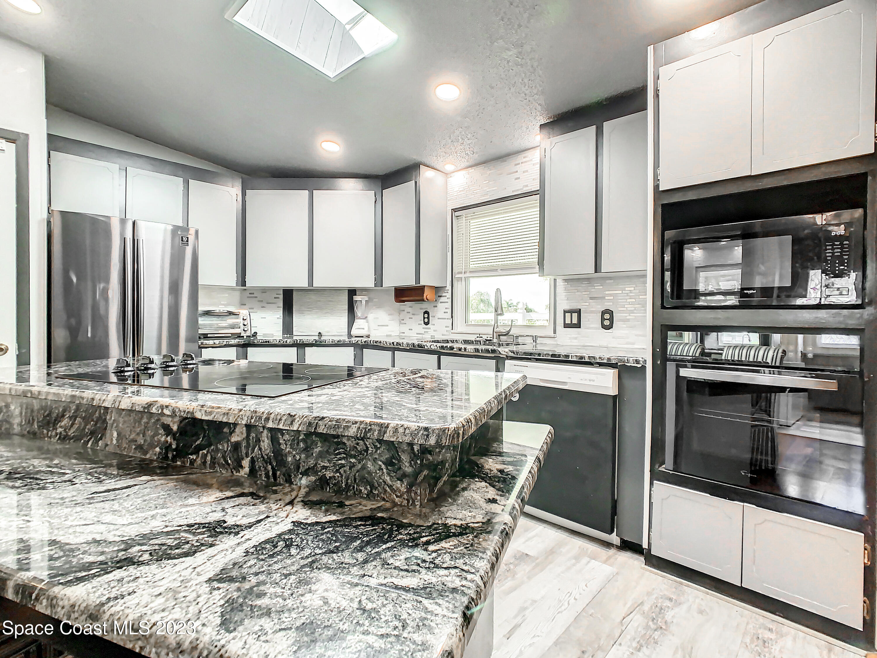 832 Periwinkle Circle Sebastian, FL 32976 - Photo 18 of 52 a kitchen with kitchen island granite countertop a stove a sink and a microwave