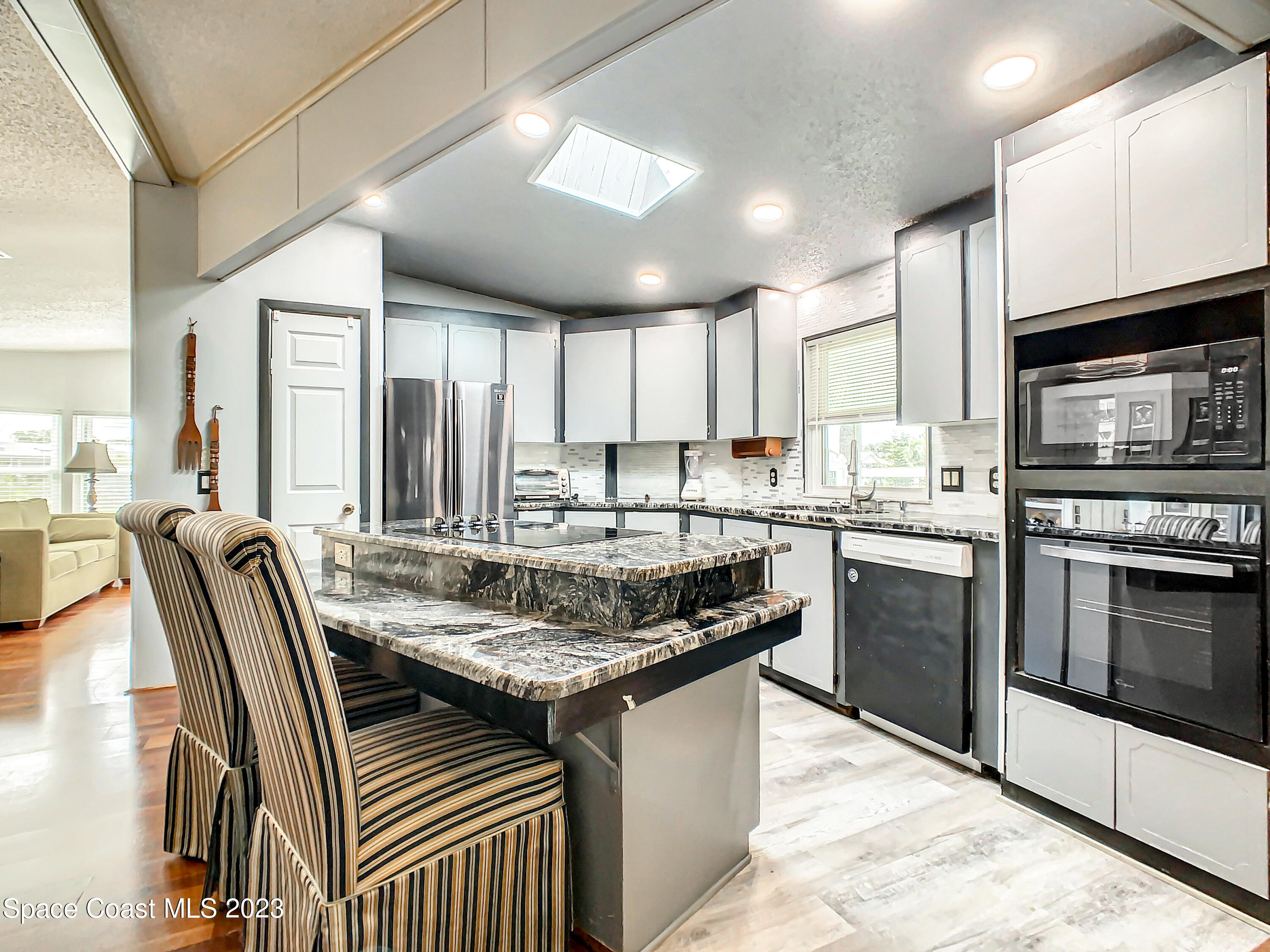 832 Periwinkle Circle Sebastian, FL 32976 - Photo 19 of 52 a kitchen with stainless steel appliances granite countertop a stove top oven a sink dishwasher a dining table and chairs with wooden cabinets
