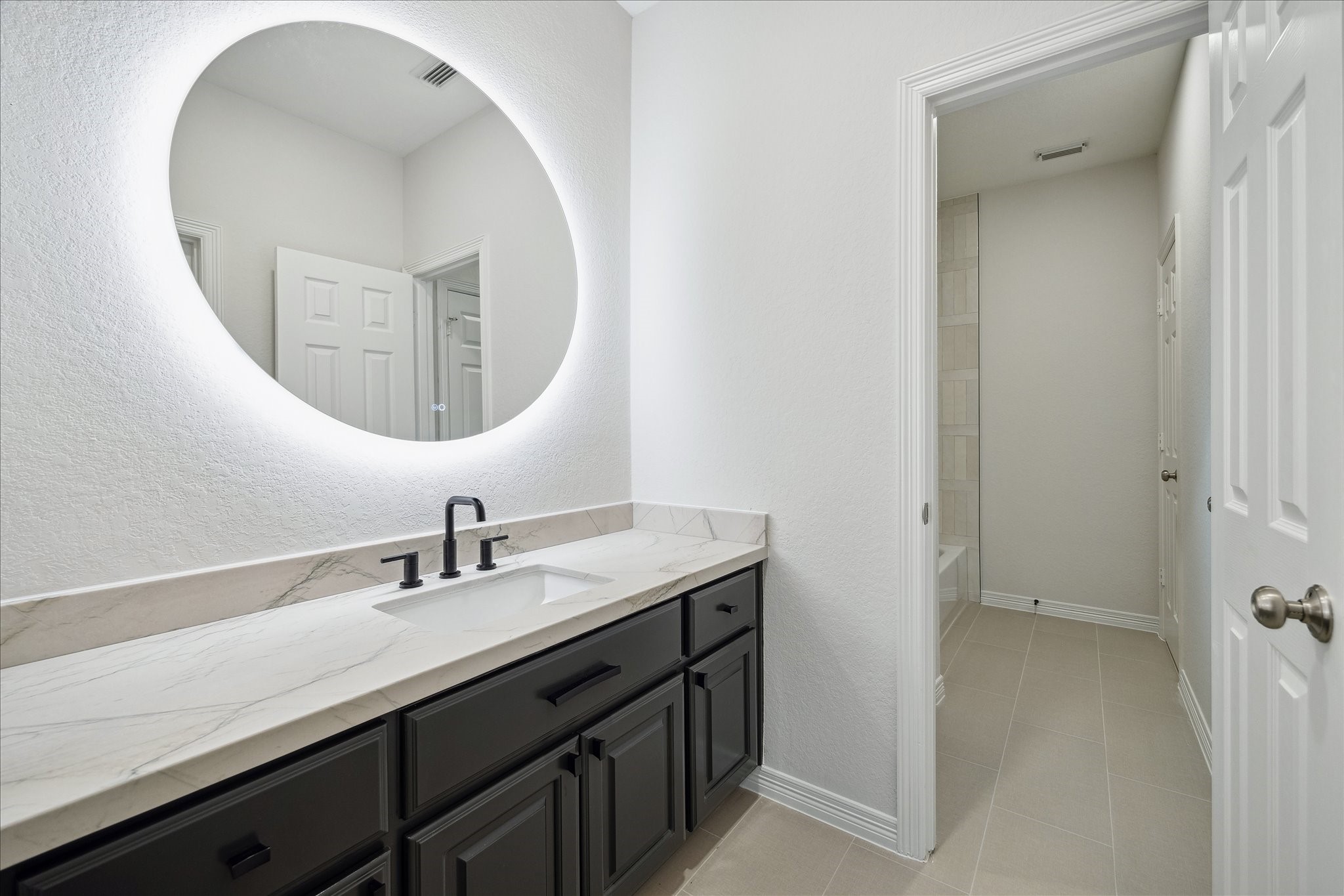 6211 Alameda Point Lane Houston, TX 77041 - Photo 41 of 50 Renovated Jack-and-Jill bathroom featuring a round mirror and modern updated finishes.
