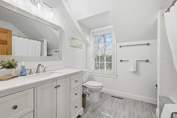 a bathroom with a granite countertop sink toilet and mirror