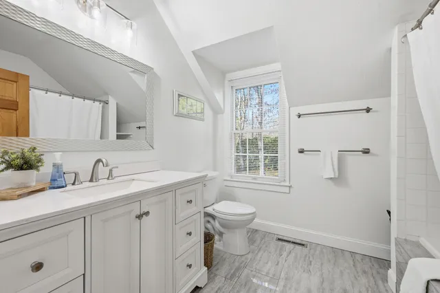 a bathroom with a granite countertop sink toilet and mirror