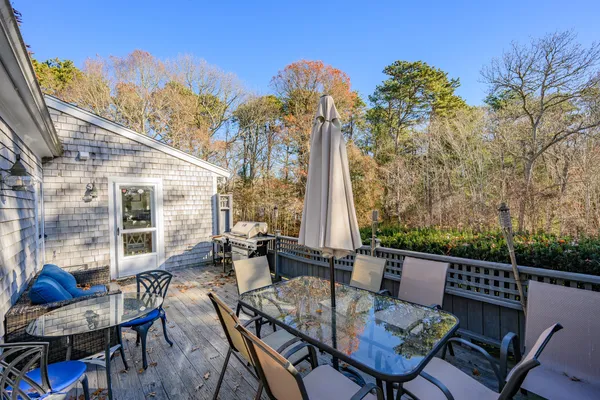a view of a patio with a dining table and chairs with wooden floor and fence