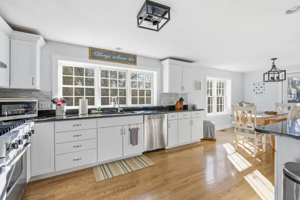 a kitchen with granite countertop a stove a sink a dining table and chairs