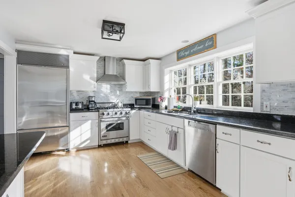 a kitchen with stainless steel appliances a stove a sink and white cabinets