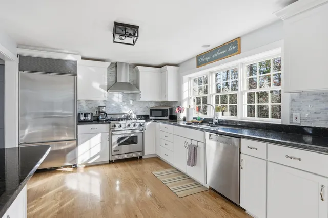 a kitchen with stainless steel appliances a stove a sink and white cabinets