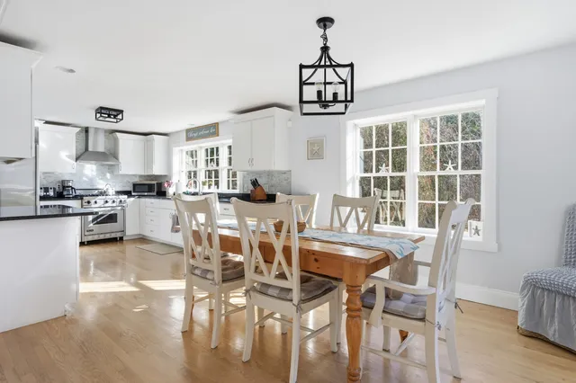 a view of a dining room and livingroom with furniture wooden floor a chandelier