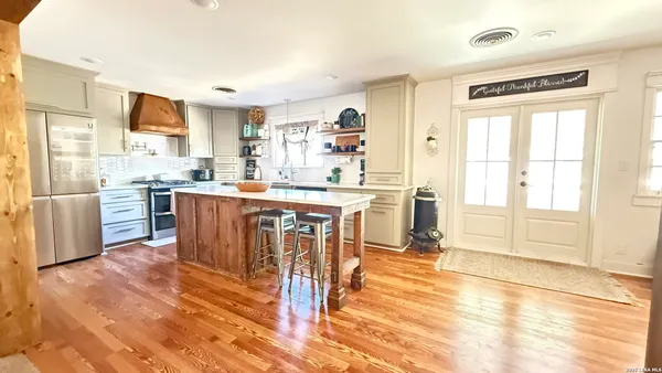 a kitchen with stainless steel appliances granite countertop a stove top oven a sink dishwasher and white cabinets with wooden floor