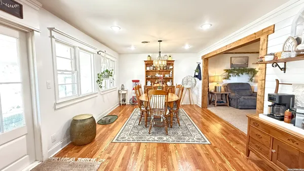 a dining room with wooden floor and large windows