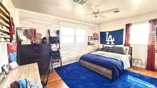 a spacious bedroom with a bed and dresser with wooden floor