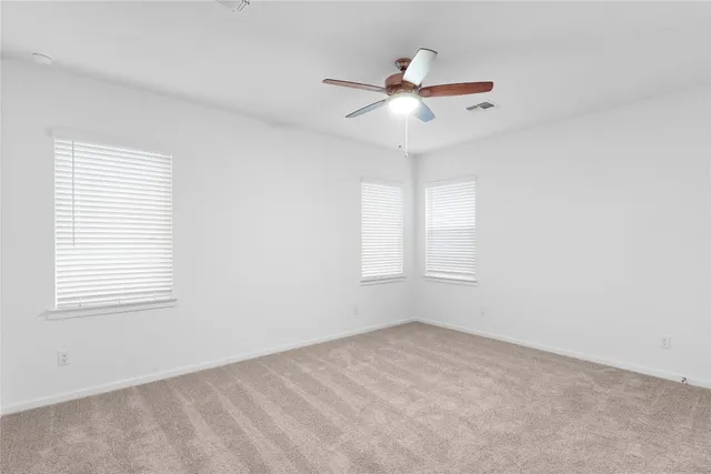 an empty room with a window and ceiling fan
