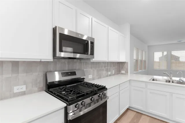 a kitchen with stainless steel appliances a sink a stove and microwave