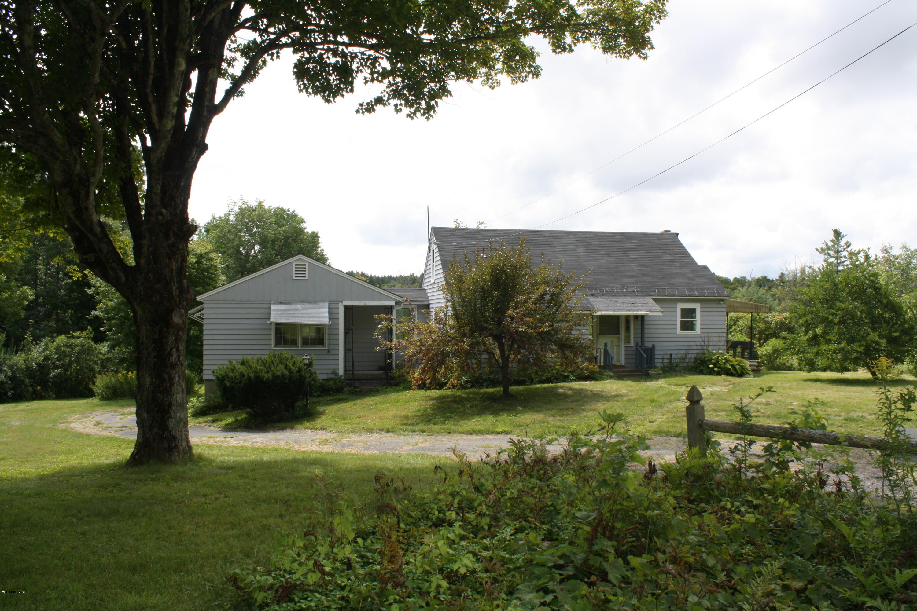 a view of a house with a big yard and large tree