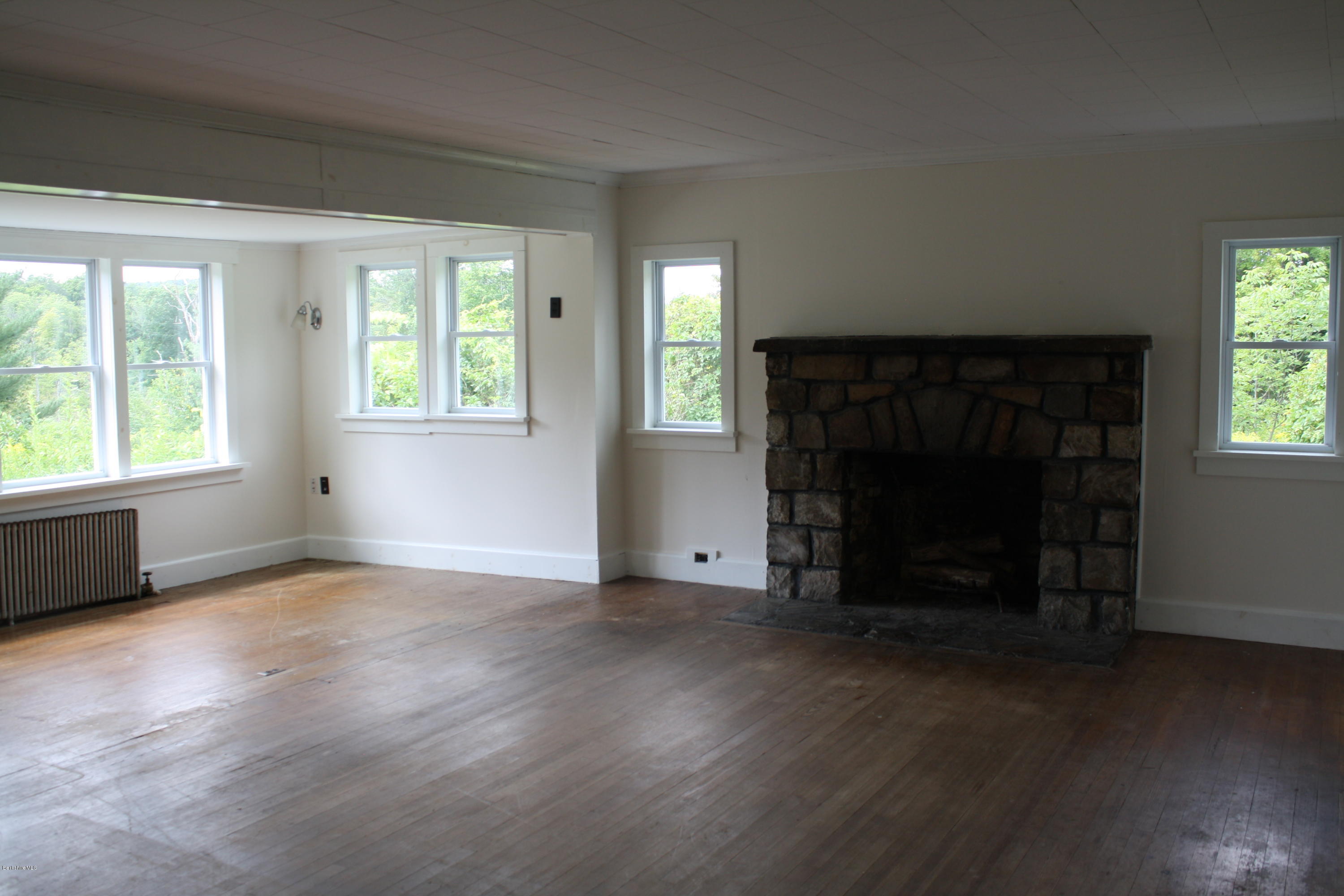 340 Main Road Monterey, MA 01245 - Photo 8 of 13 an empty room with wooden floor a fireplace and windows