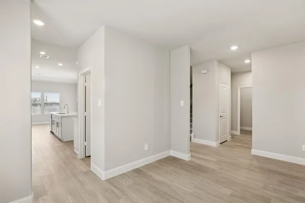 a view of a hallway with wooden floor a sink and a refrigerator