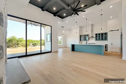 a view of an empty room with a window and kitchen view