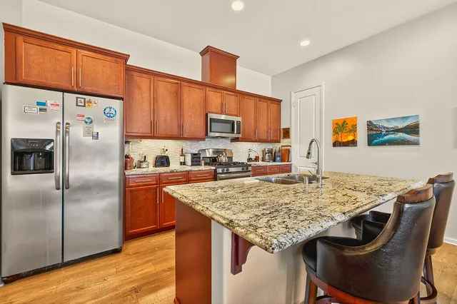 a kitchen with stainless steel appliances granite countertop a table chairs sink refrigerator and microwave