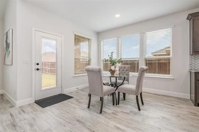 a dining room with wooden floor and a floor to ceiling window