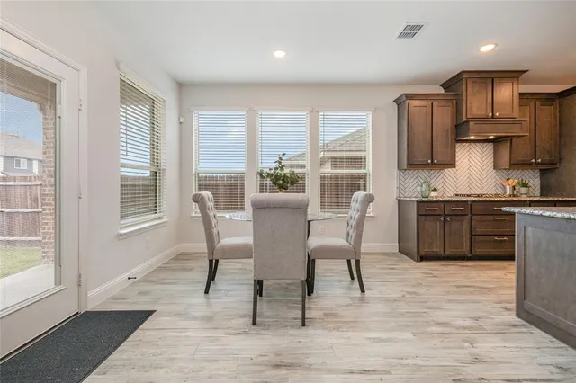 a kitchen with stainless steel appliances granite countertop a stove top oven a sink dishwasher a dining table and chairs with wooden floor