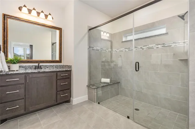 a bathroom with a granite countertop sink a mirror a window and a shower