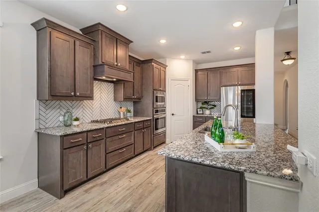 a kitchen with stainless steel appliances granite countertop a sink stove and refrigerator