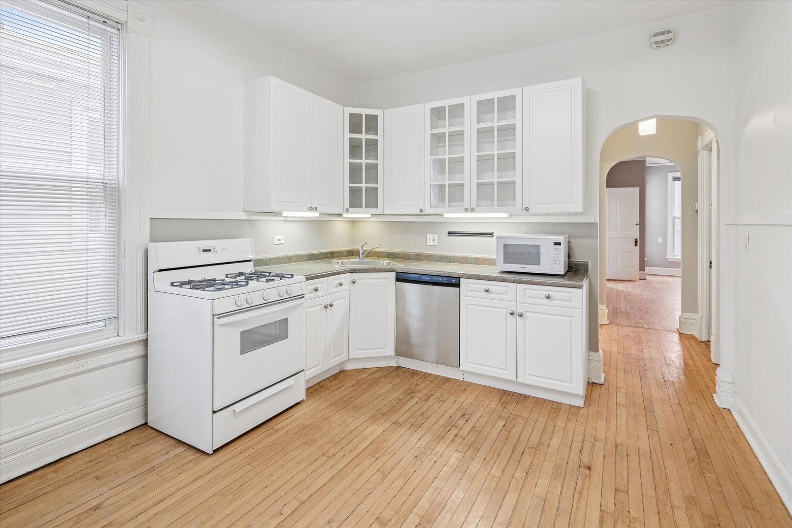 3818 North Hermitage Avenue, Unit 2 Chicago, IL 60613 - Photo 5 of 16 a kitchen with a white cabinets stove and wooden floor