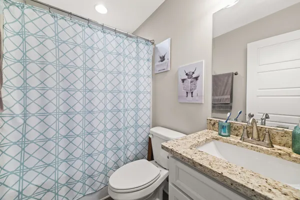a bathroom with a granite countertop toilet sink and mirror
