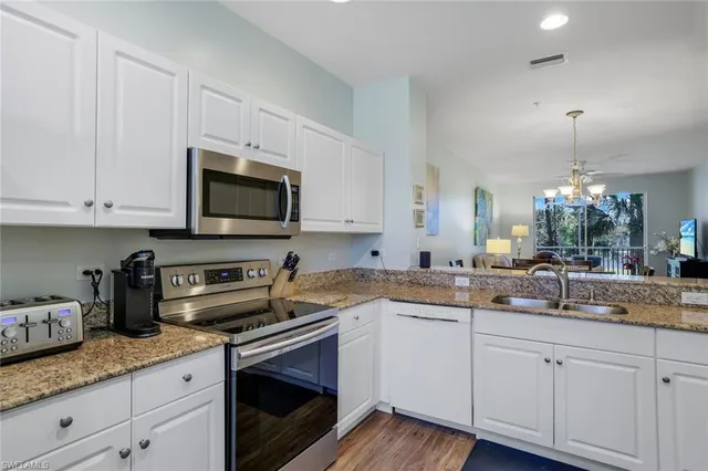 a kitchen with granite countertop white cabinets stainless steel appliances a sink and wooden floor