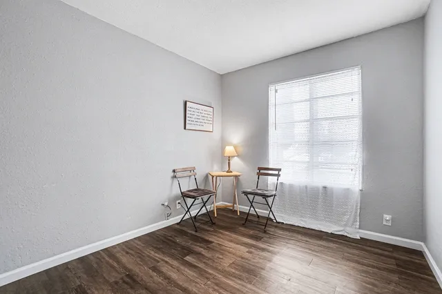 a workspace room with wooden floor a glass table and windows