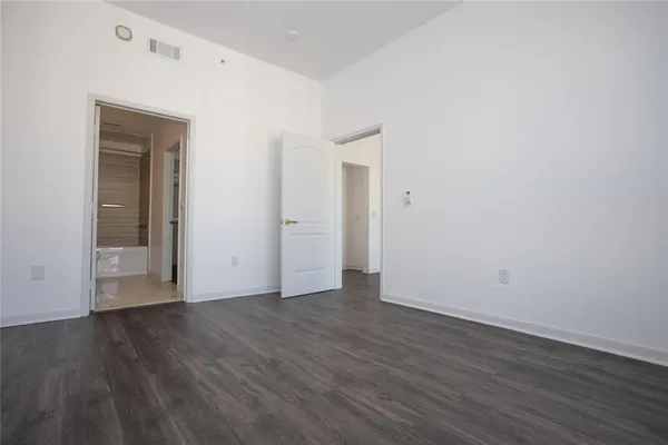 a view of an empty room with wooden floor and closet