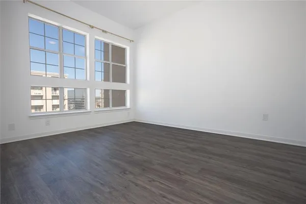 a view of an empty room with wooden floor and windows