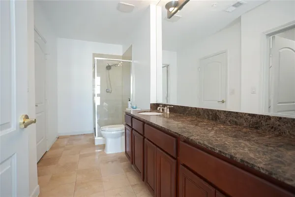 a bathroom with a granite countertop sink a toilet and shower